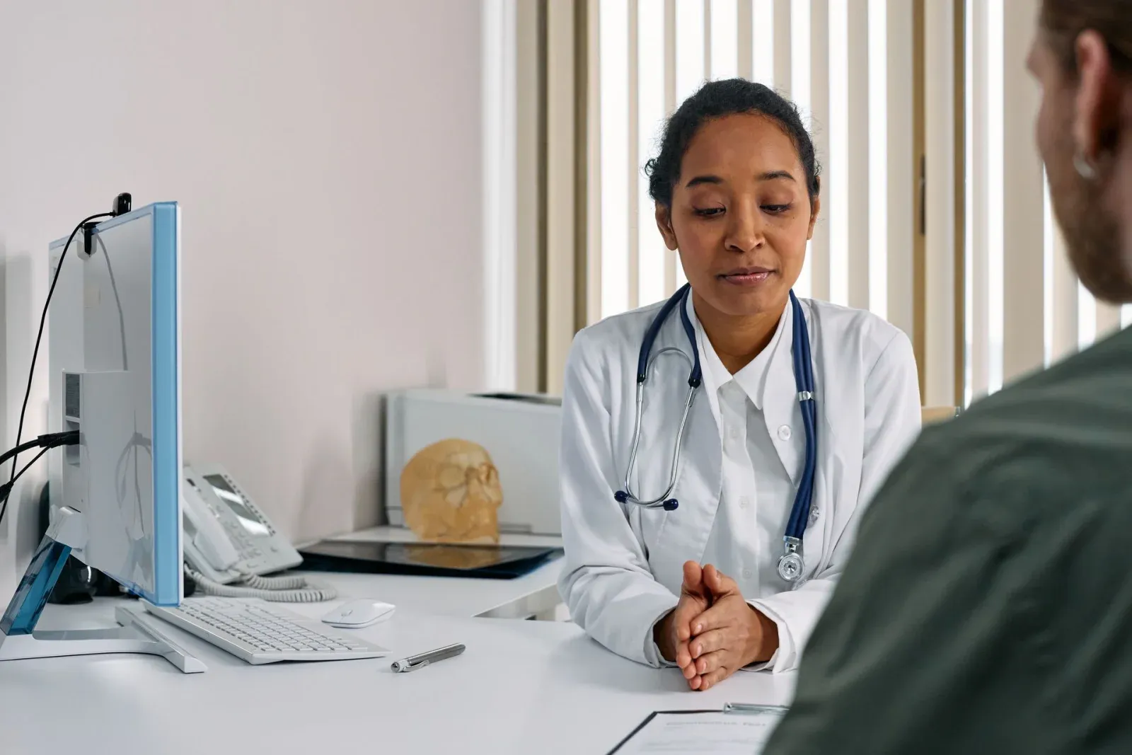 A clinician consulting with a patient at a desk.